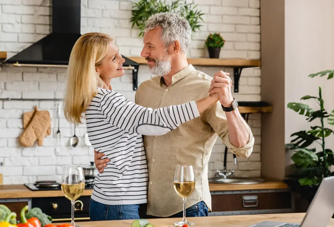 A couple dancing in the kitchen of their new home after getting a mortgage, even though they are over 50.